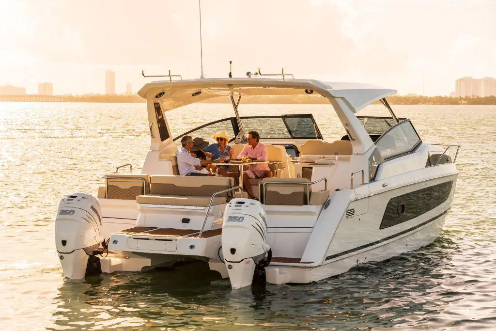 Four people enjoying a leisurely meal on a luxury motorboat, with a golden sunset reflecting on the water.